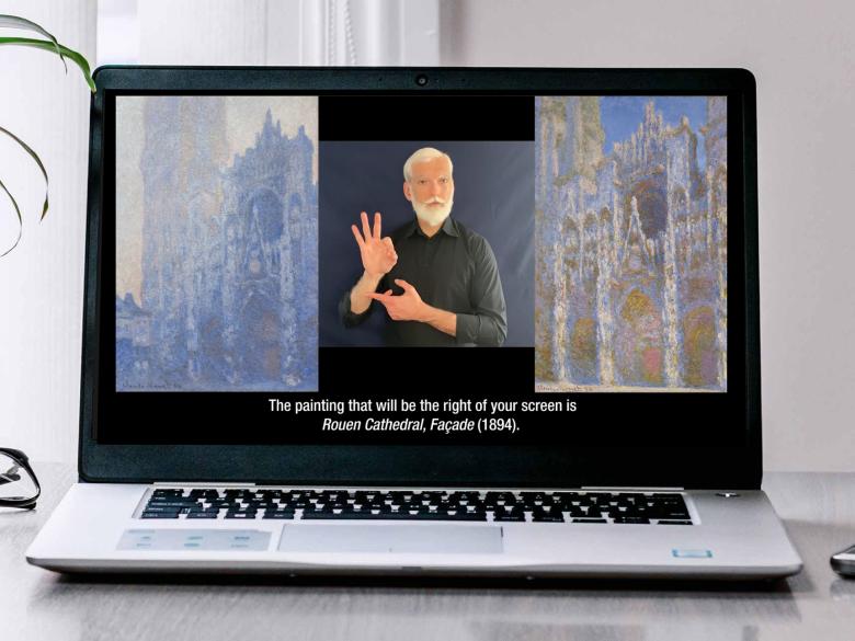 A laptop on a desk showing a still from a virtual ASL program 