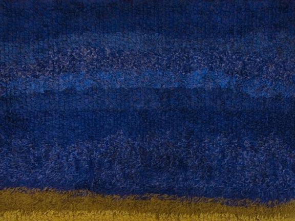 A detail of a deep blue tapestry with a tan bottom hem. 