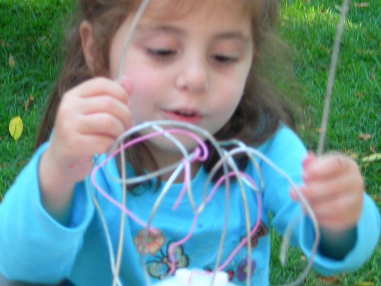 Young girl making sculpture with wires outside