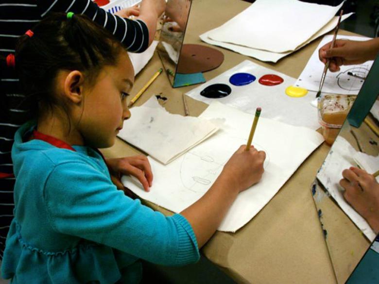 girl in green shirt holding pencil, drawing