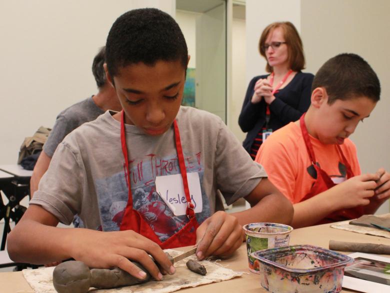 boys in aprons making things out of clay