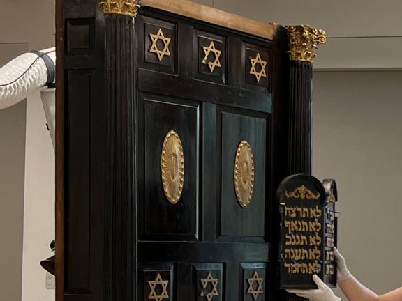 A partial view of a deep brown and gold Torah ark in a conservation studio. 