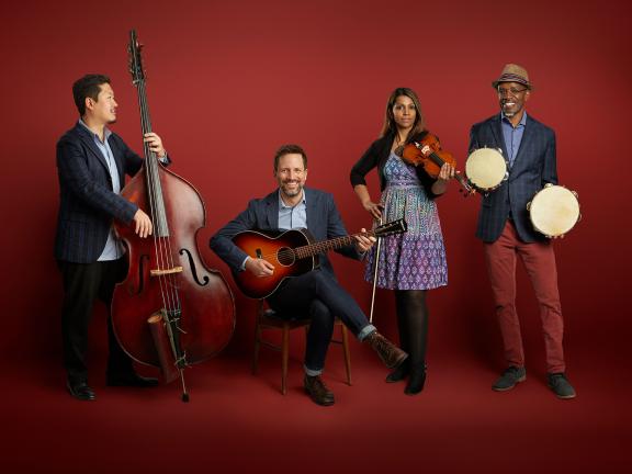 Members of American Patchwork Quartet pose with their instruments against a red backdrop