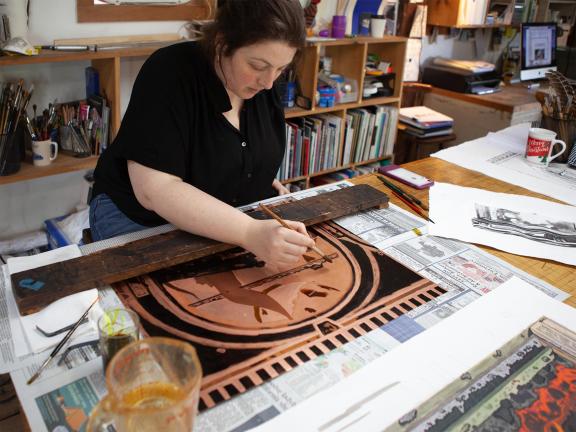 Photograph of a female artist working on a plate.