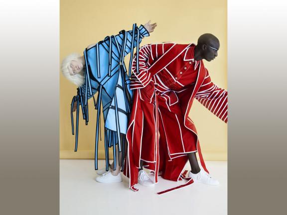 Photograph of 2 women, one in blue and black outfit, one in red and white outfit.
