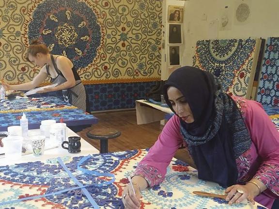 Ambreen Butt at work; woman decorating cloth