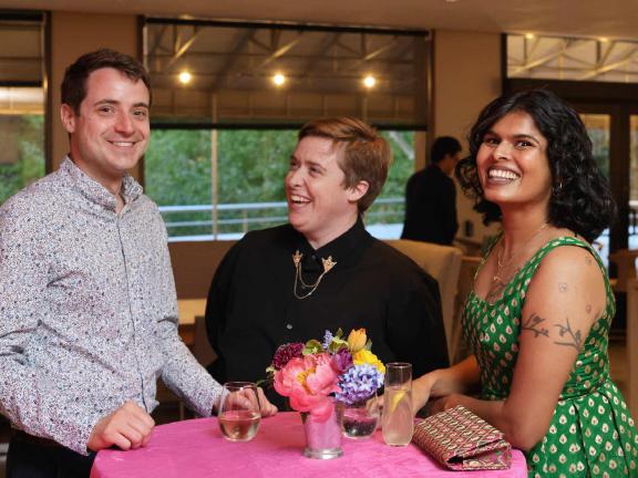 Three smiling guests standing around cocktail table at reception in 465 Restaurant