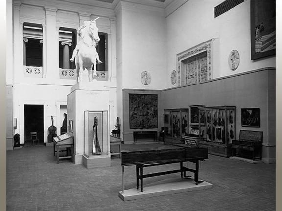 Black white photograph of museum gallery with musical instruments on display