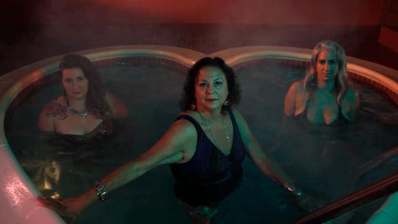 Still from film depicting three women in a heart-shaped hot tub