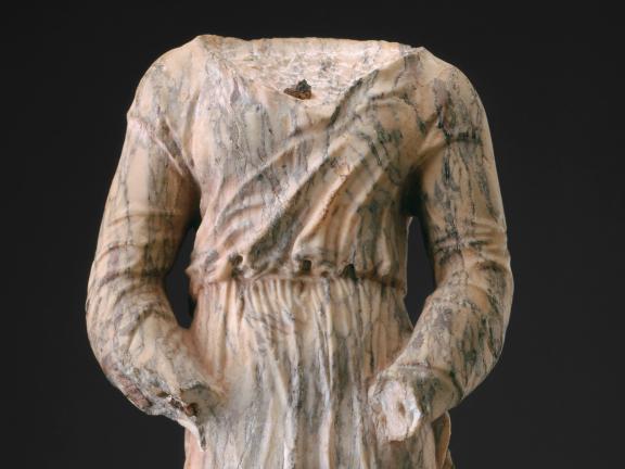 A detail of a variegated purple and white marble sculpture of a barbarian whose head and hands are missing