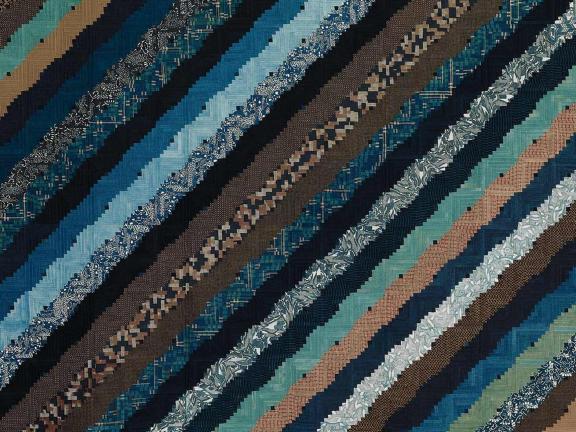 Fabric quilt with diagonal strip design in blues, browns, and green colors.
