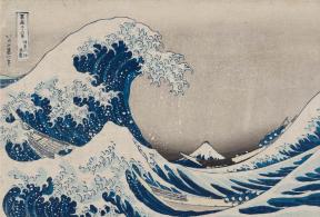 A bright blue tidal wave crests on choppy waters with a mountainscape in the distance.