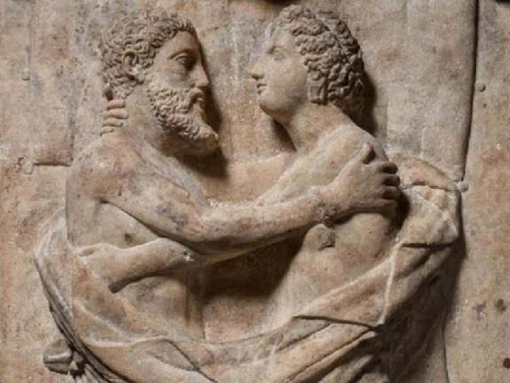 A detail of a sarcophagus and lid carved with the figures of a husband and wife. 