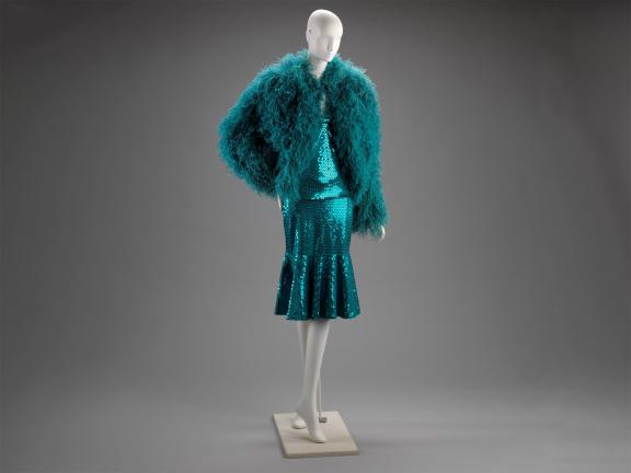 Mannequin wearing a turquoise dress with a sequined skirt and ostrich feather top