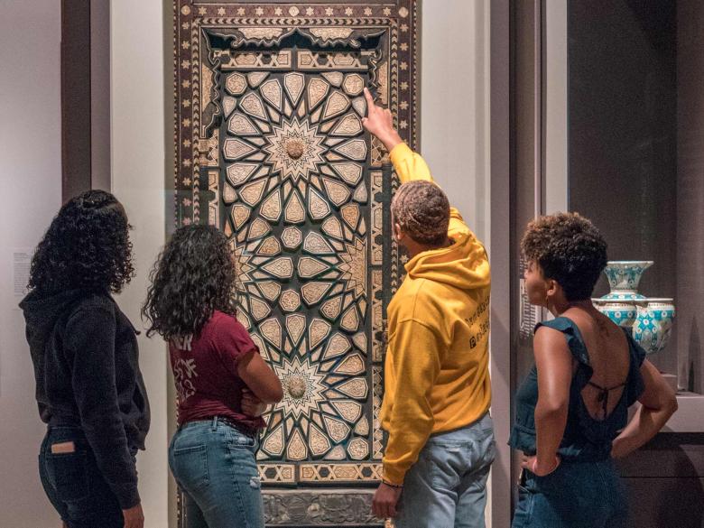Four interns look at a piece of art in the Art of Islamic Cultures gallery 
