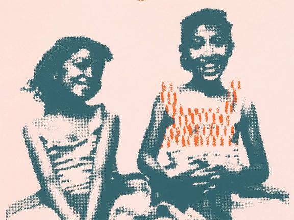 Photograph of two smiling and seated young girls.