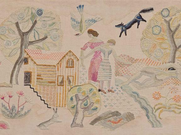 An embroidered linen scene of women, animals, and trees outside of a country home. 