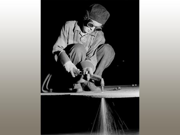 black-and-white photograph of a woman wearing goggles and welding.