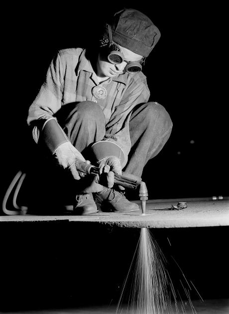 An image of a women wearing goggles and welding.