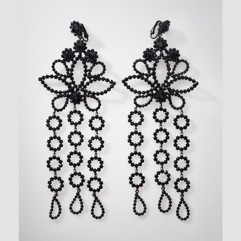 A pair of black glass earrings with a floral design and three dangling pieces.
