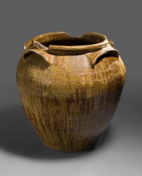 A light orangey-brown jug engraved with text and adorned with a large opening and three handles.