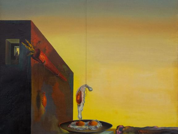 A building at sunset has a large carrot affixed to its side; two eggs on a plate sit on the building white one egg hangs above the plate from a string. 