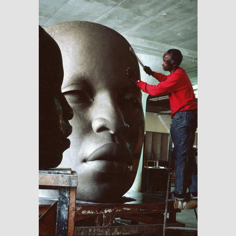 John Wilson working on clay sculpture head with African-American features and closely cropped hair