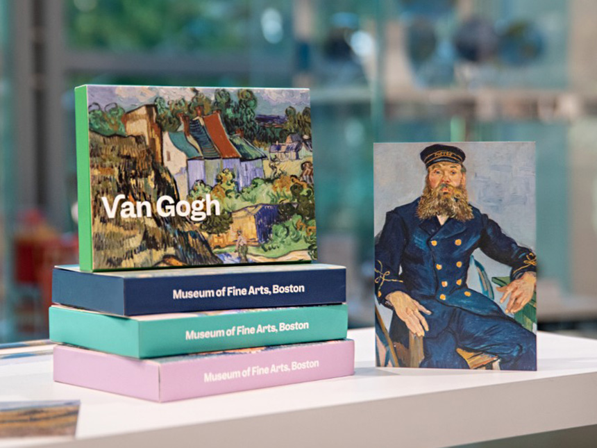 Arrangement of boxes of postcards featuring Van Gogh paintings, next to postcard standing up depicting Van Gogh's postman portrait