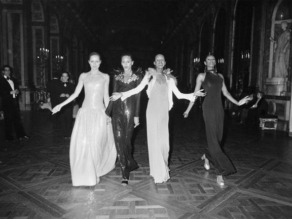 A still from the film the 2012 Versailles '73: American Runway Revolution of four models walking down a hallway.