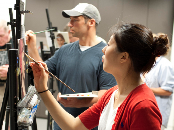 Two adult students paint on easels in classroom SAC